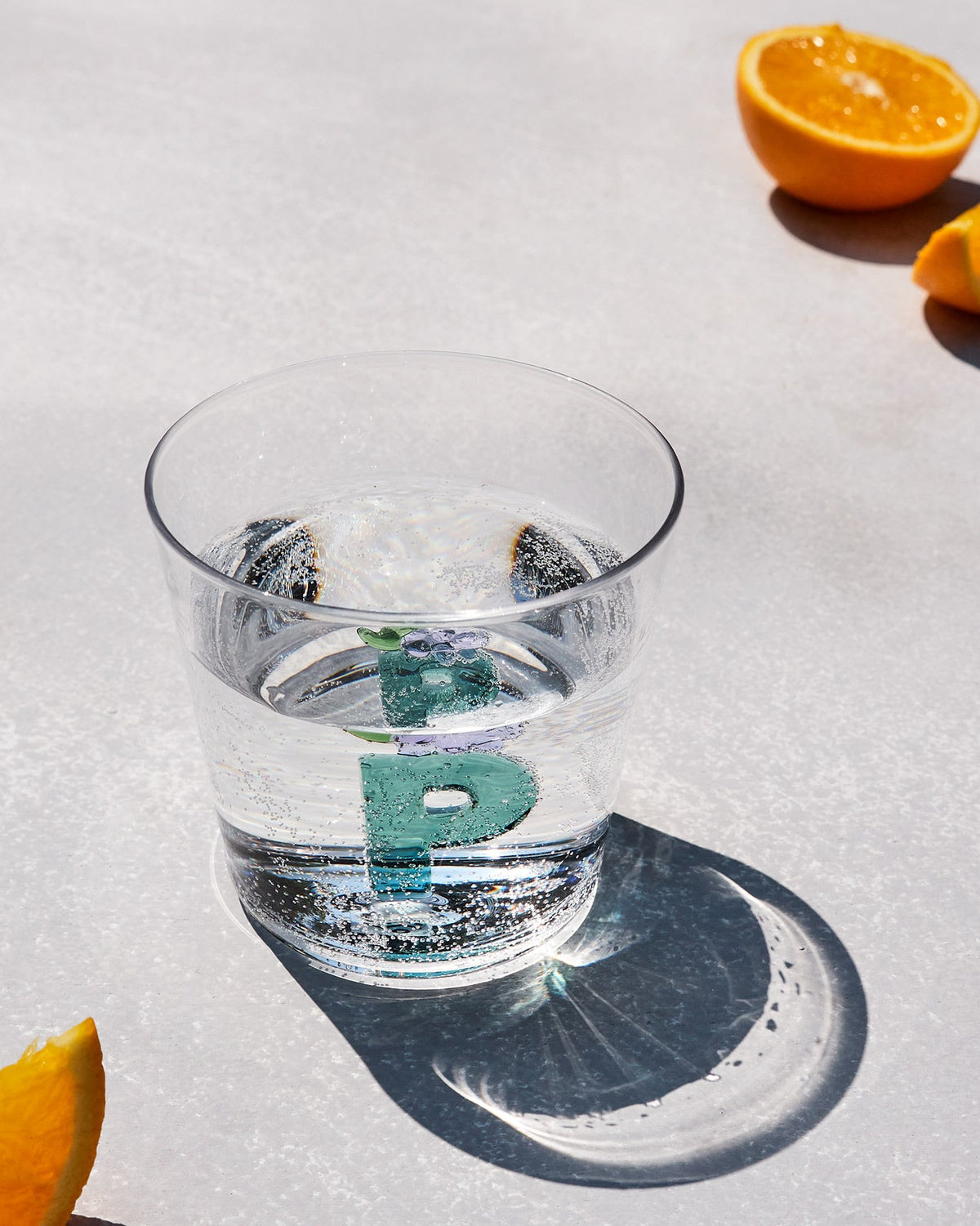 Alphabet Glass P filled with sparkling water, teal letter P at the base.