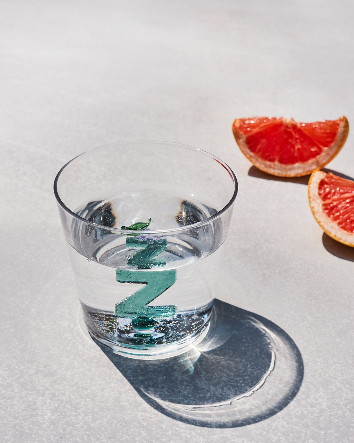 Clear Alphabet glass with a teal letter Z, half filled with water.