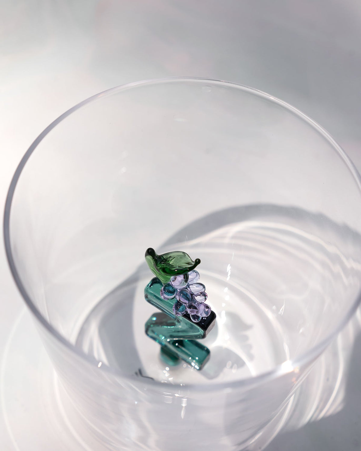 Overhead view of an Alphabet glass with a teal letter Z and purple grapes.