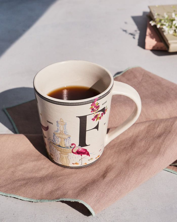 Firefly mug with letter F, flamingo, and fountain motifs filled with a dark drink.
