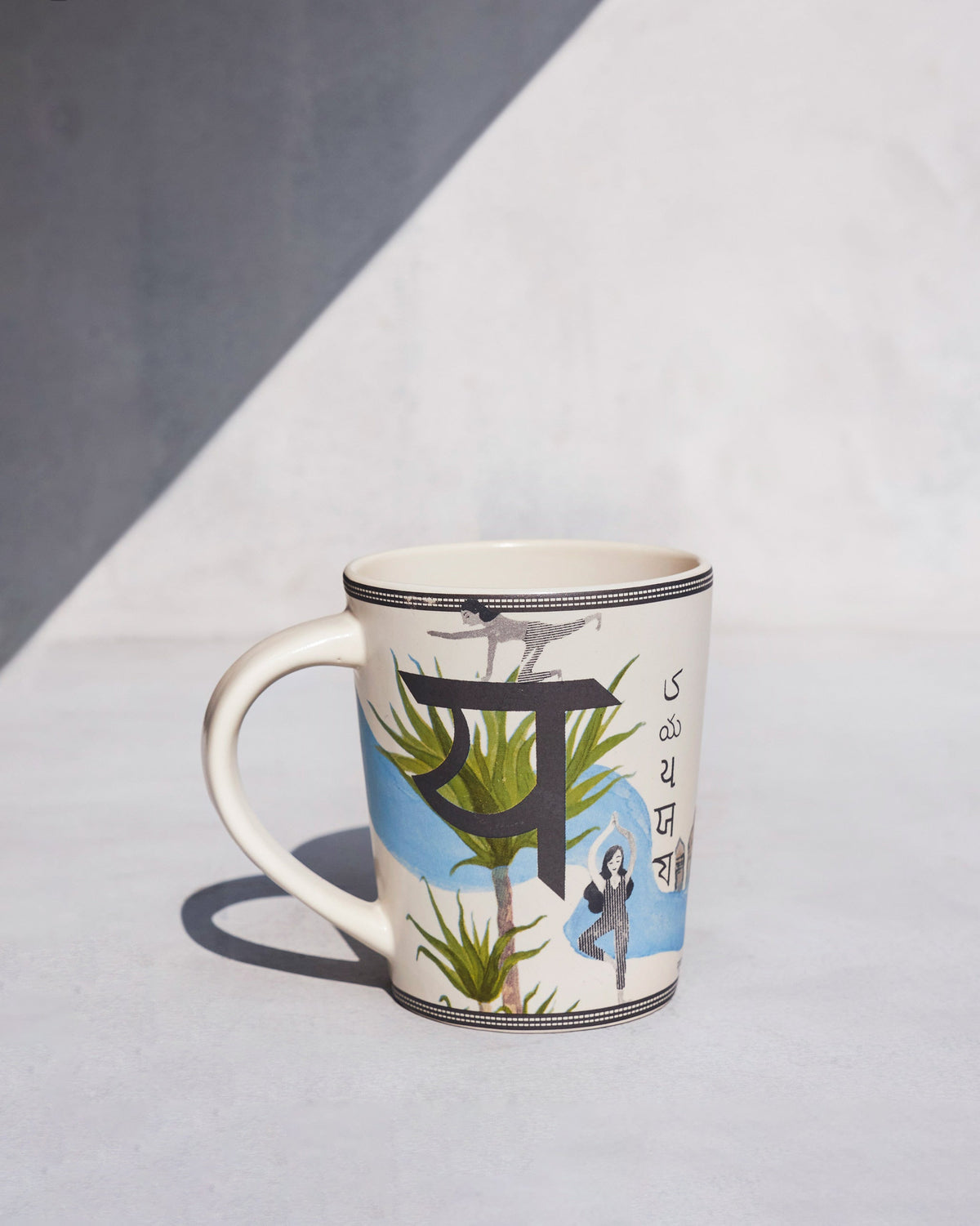 Cream Yoga mug with a Devanagari letter, palm plants and a yoga tree pose.