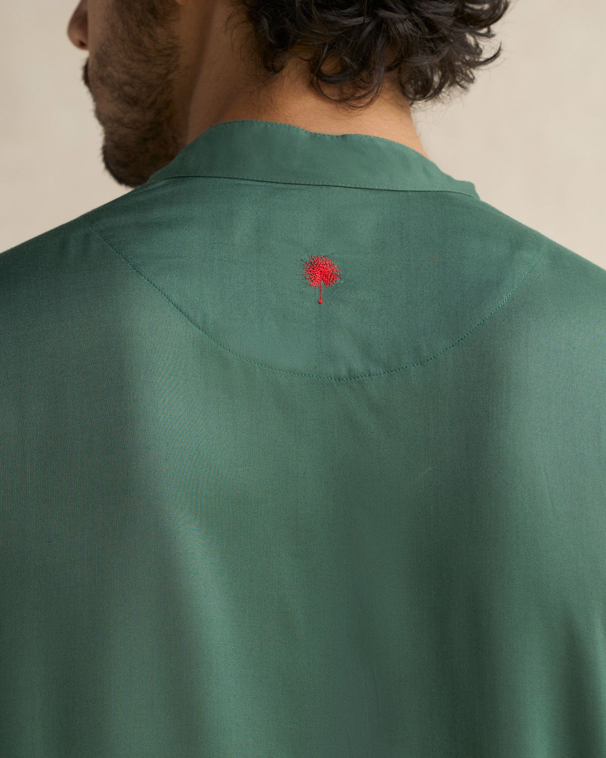 Back of a deep green Long Pleated Kurta showing a small red embroidery on the yoke.