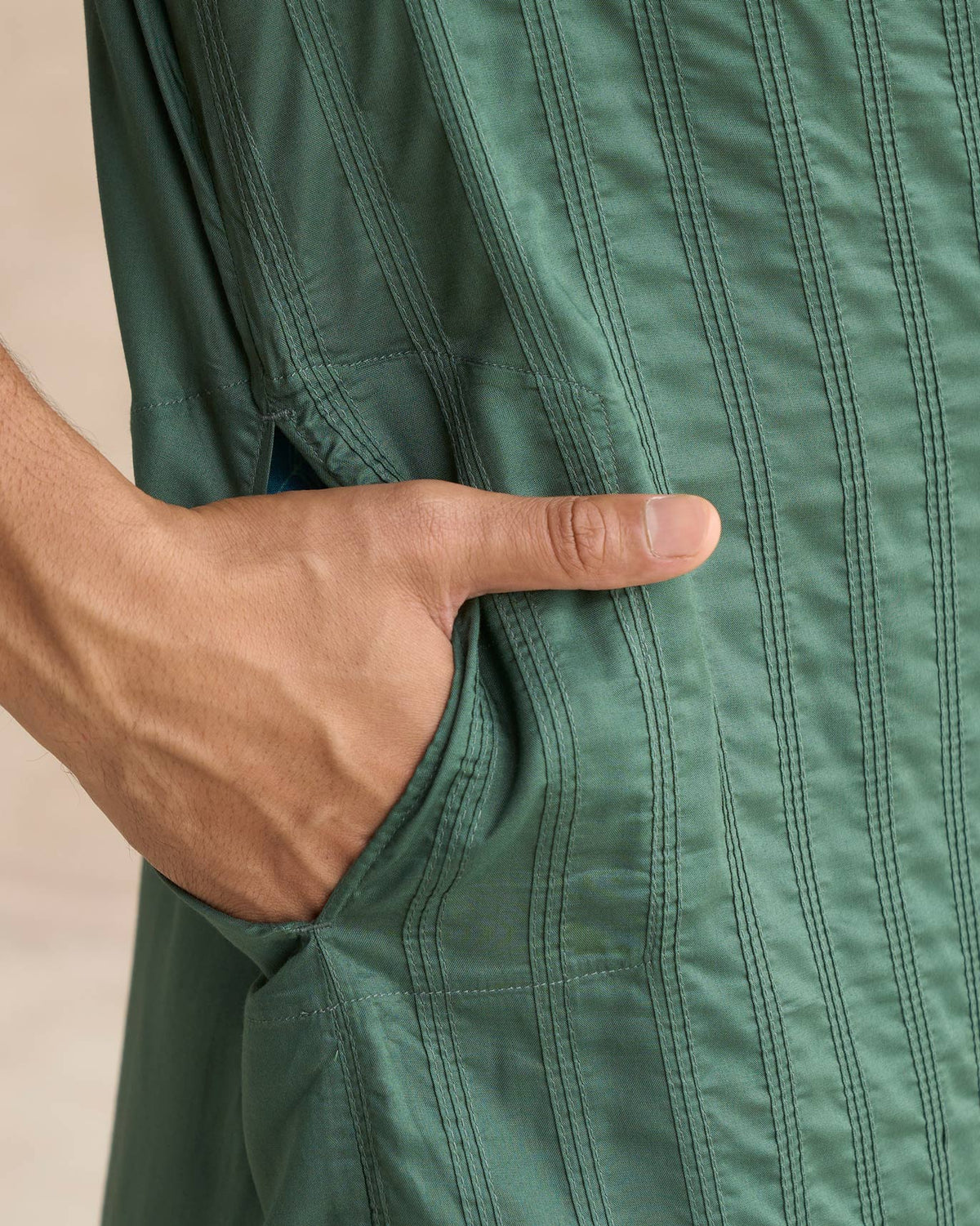 Close-up of a deep green Long Pleated Kurta showing the side pocket and vertical pleats.