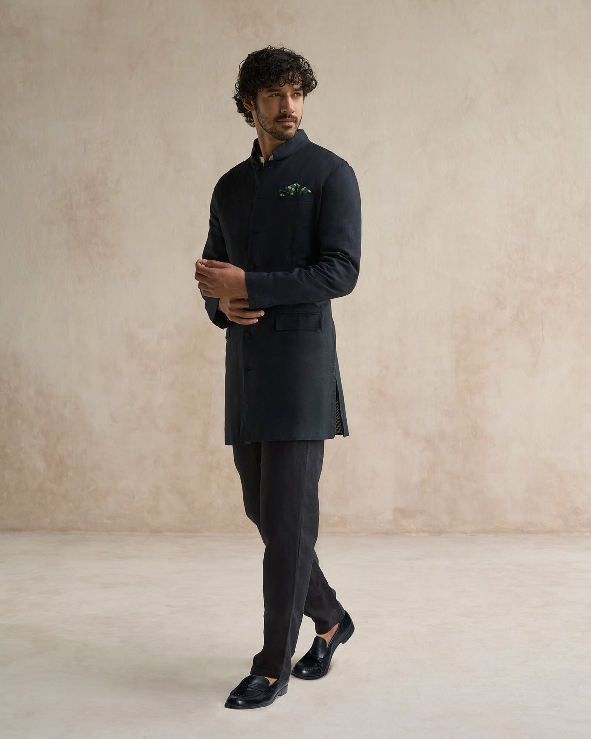Person wearing a black Negombo bandhgala, hands folded at the front.