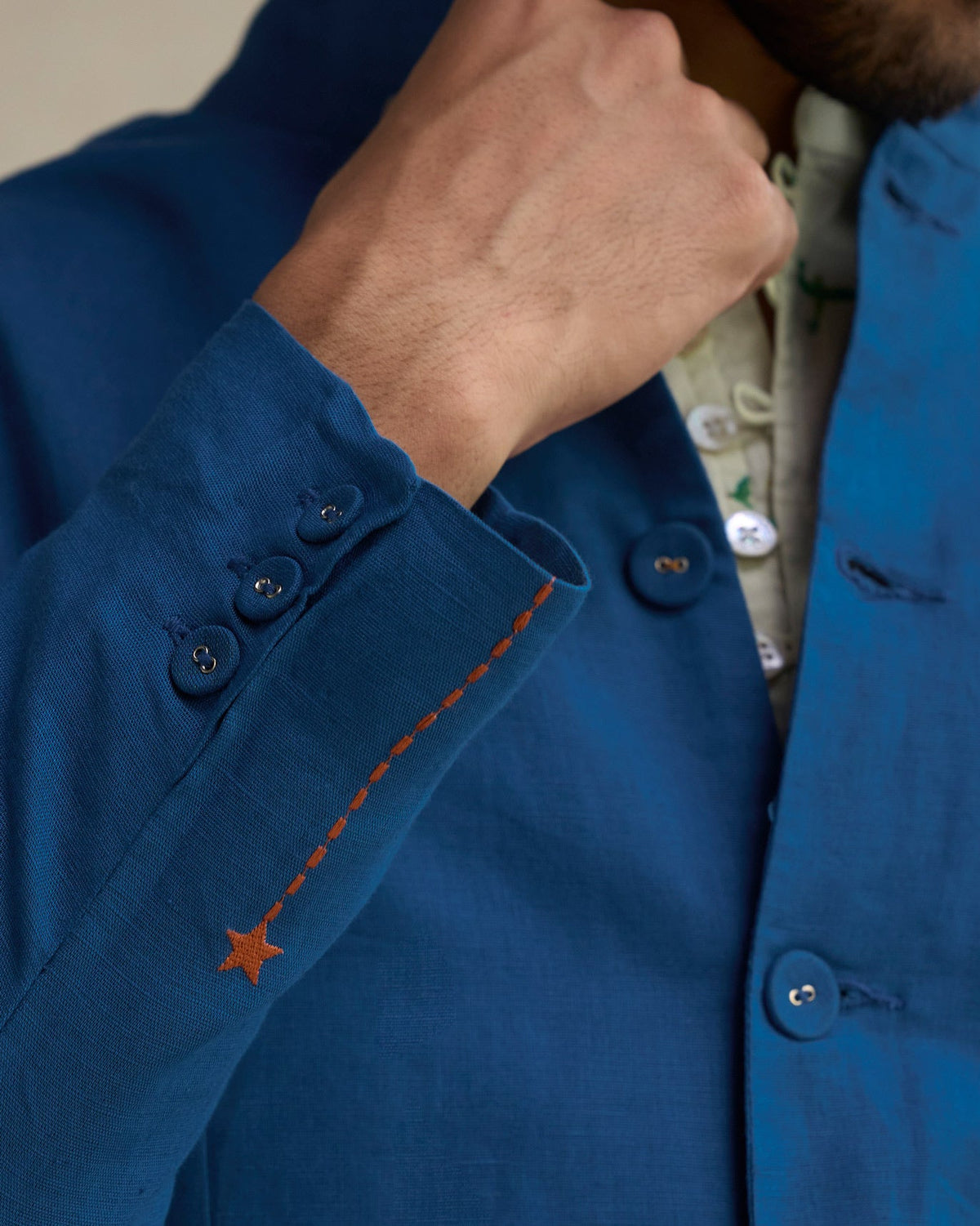 Close-up of a Negombo Bandhgala cuff showing orange star stitching and buttons.