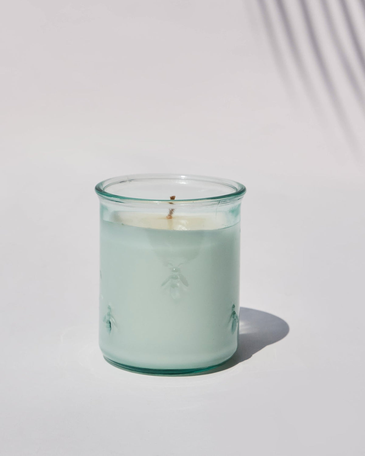 Firefly Candle with embossed bees on its pale green glass.