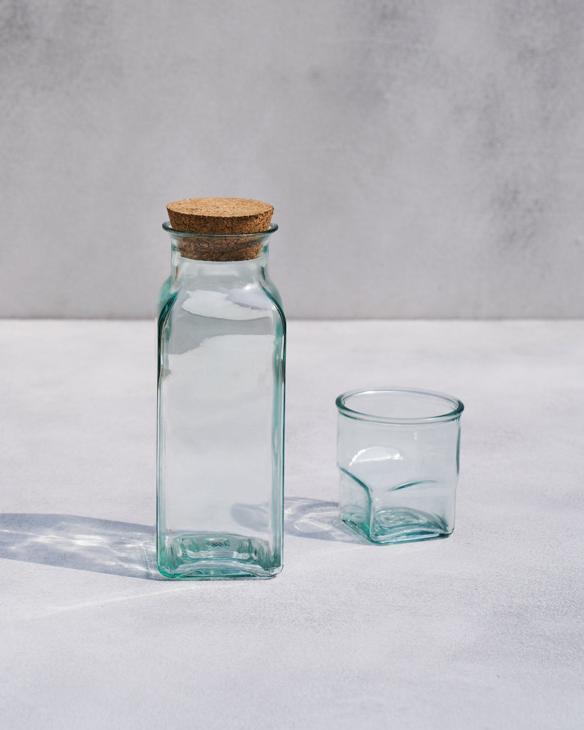 Ibis Tumbler & Carafe with a cork stopper in its neck, beside a glass tumbler.