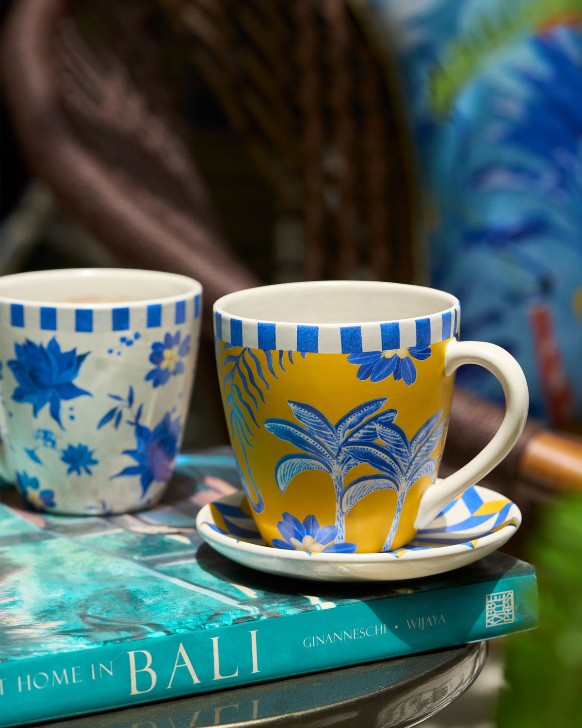 Yellow and cream Panas conical mugs with blue palm and floral motifs.