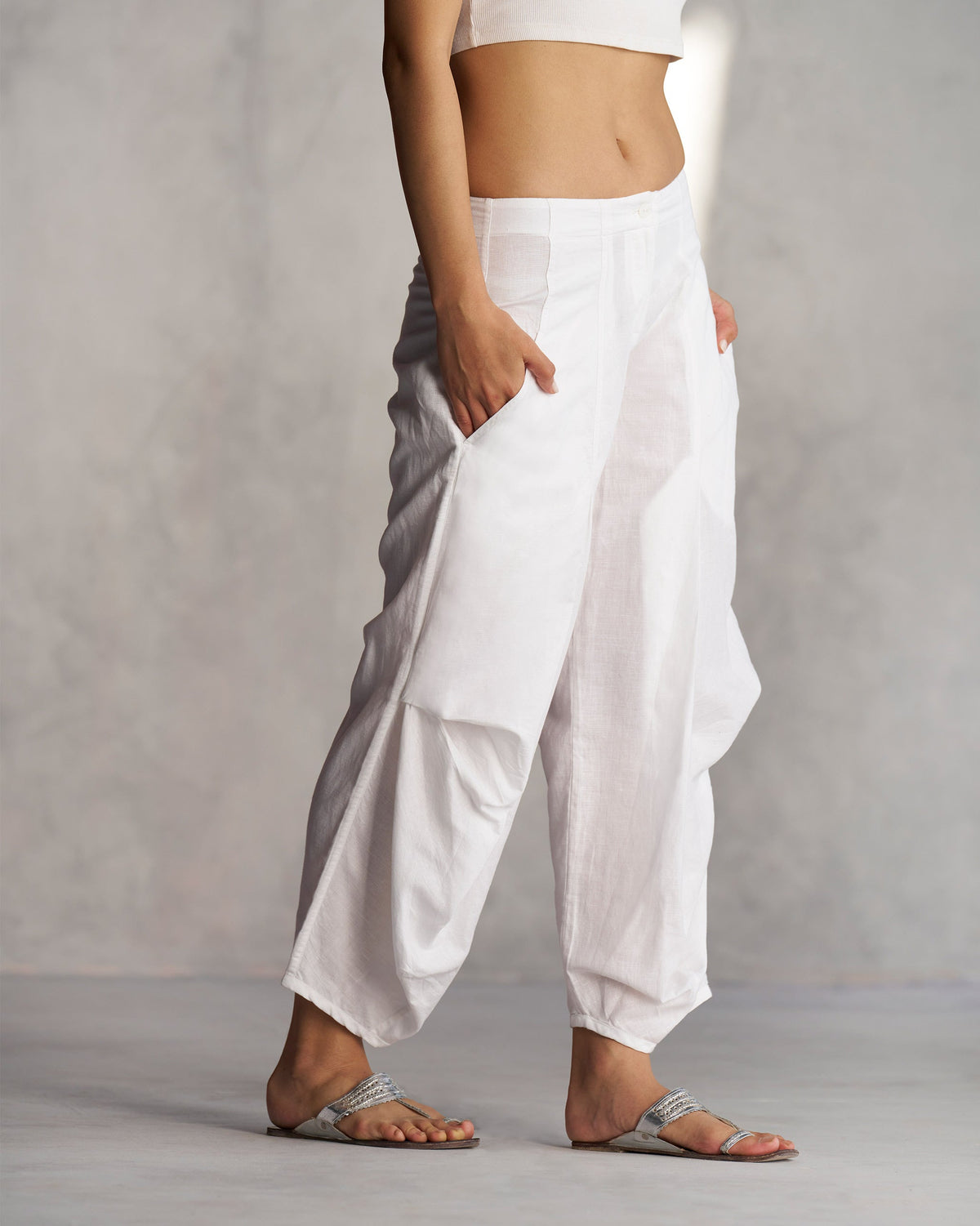 Side view of Weekend Trousers in white with a hand in the pocket.