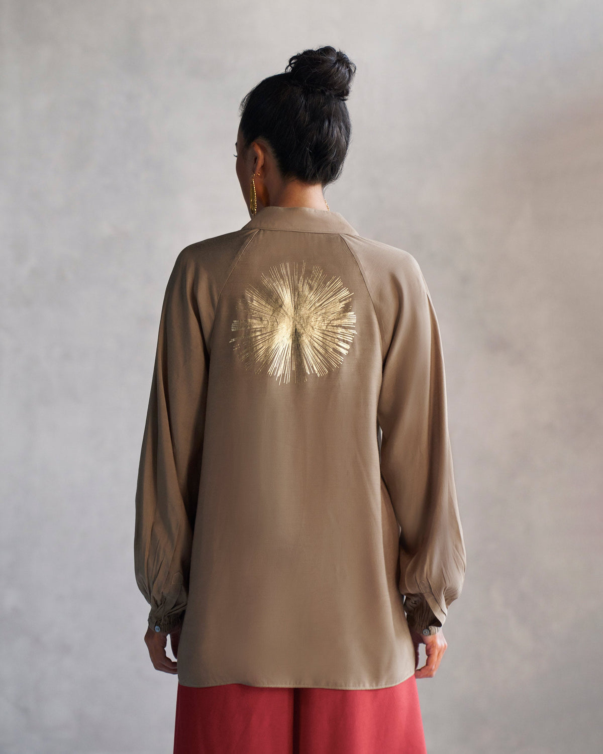 Back of an oak brown raglan blouse with a gold sunburst print.
