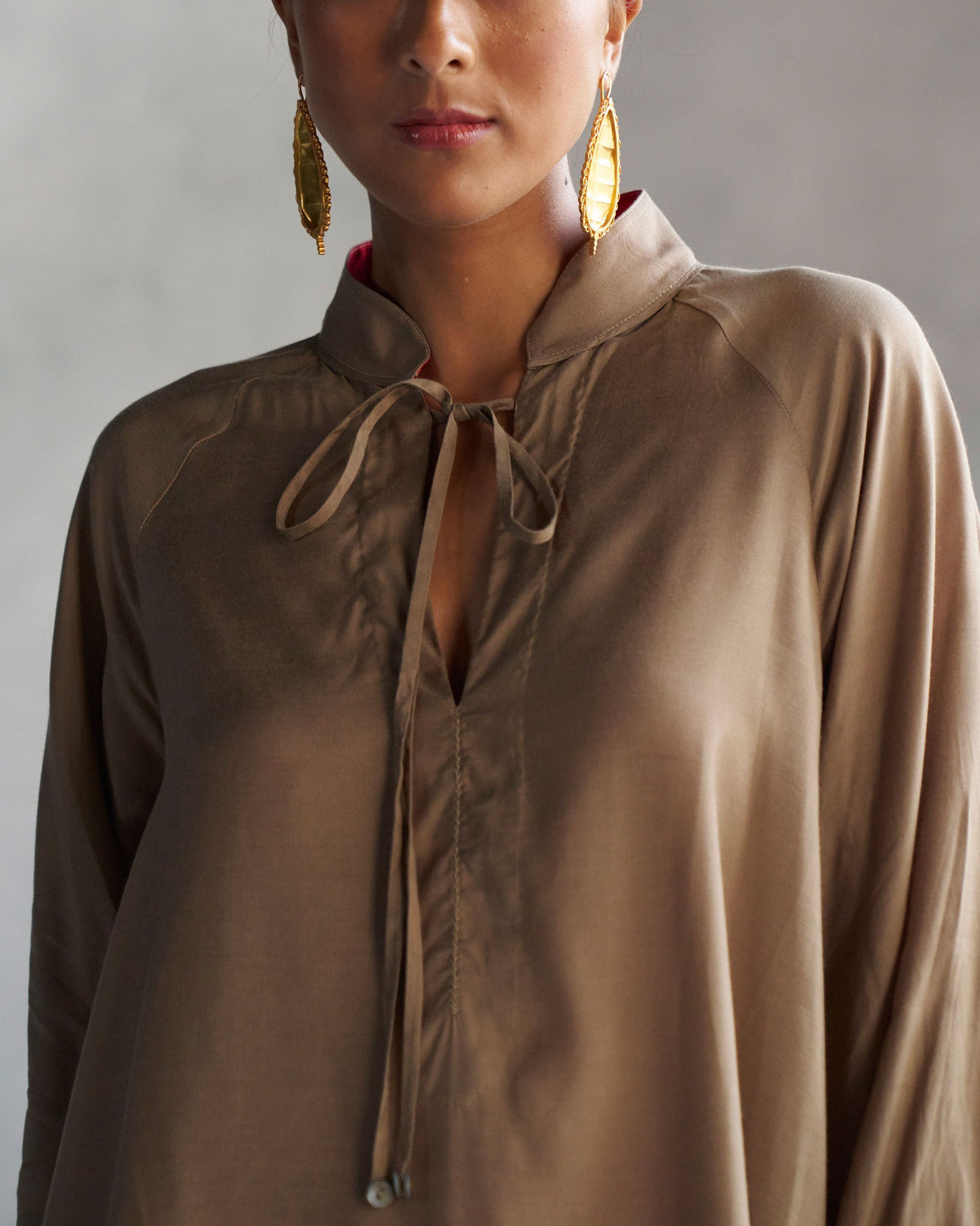 Close-up of collar ties on an oak brown raglan blouse.