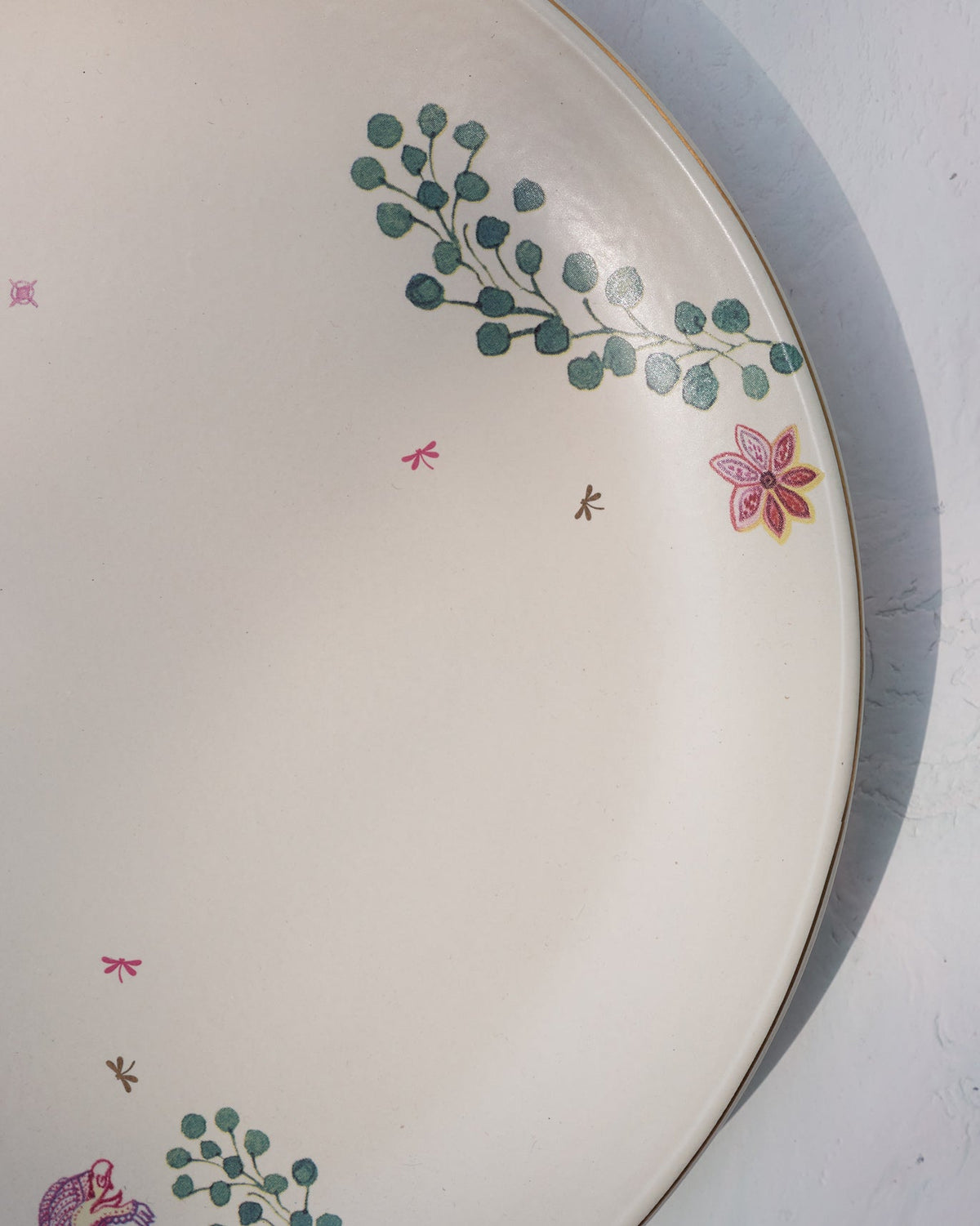 Close-up of the Barong Dinner Plate showing a pink flower and eucalyptus sprig.