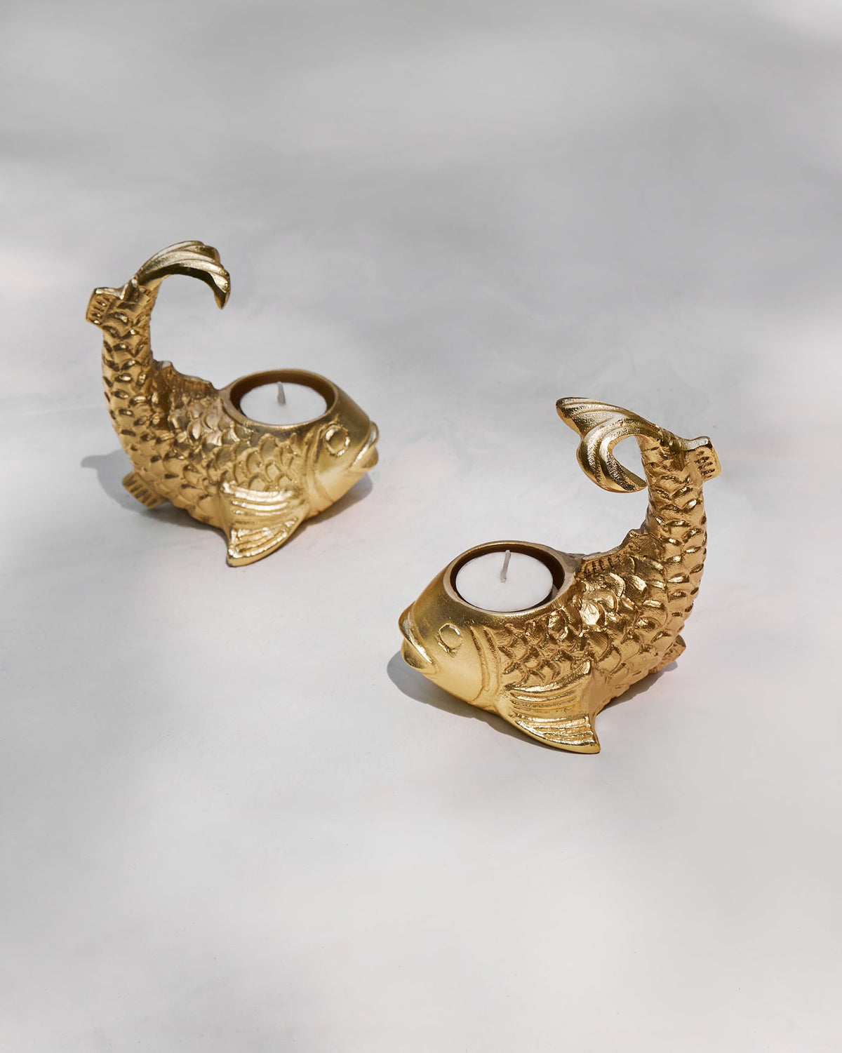 Pair of Dory Tea Light Holders shaped like gold fish on a pale surface.