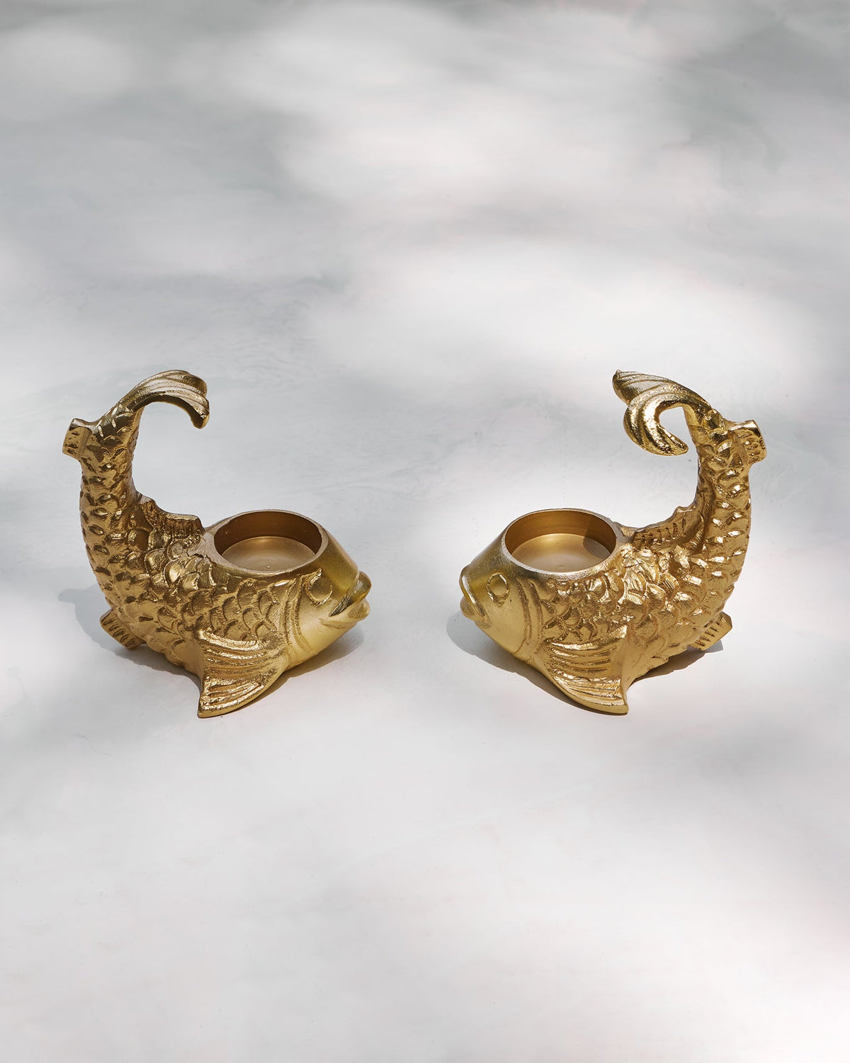 Two gold fish-shaped Dory Tea Light Holders, each with a tea light cup, on a pale surface.