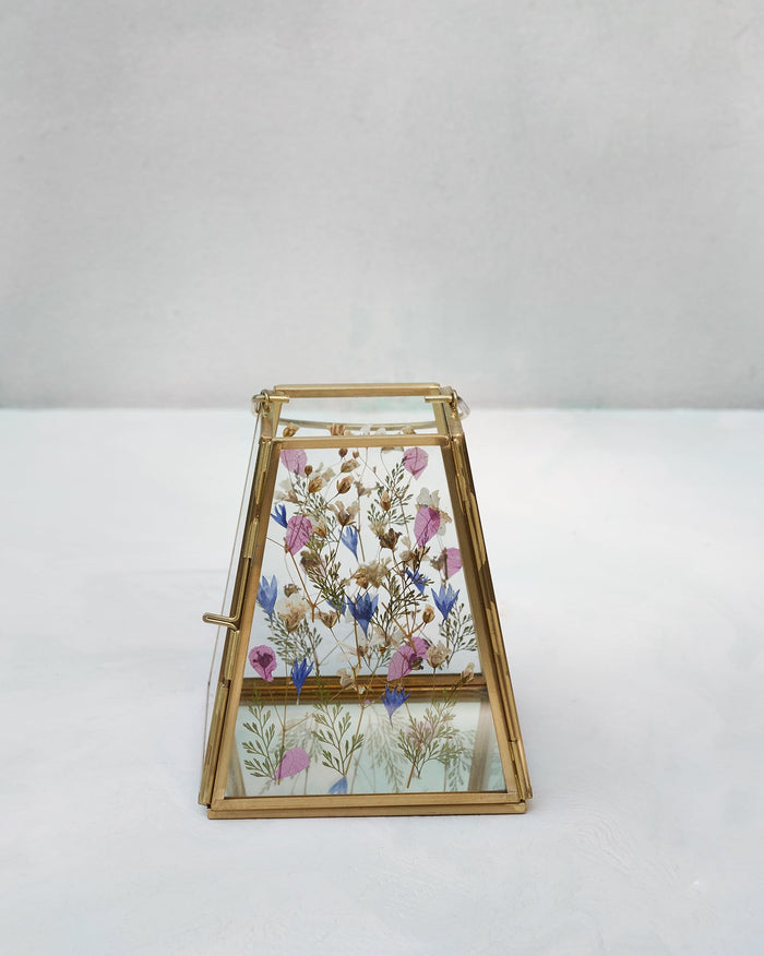 Gold-framed glass lantern with pressed flowers visible inside.