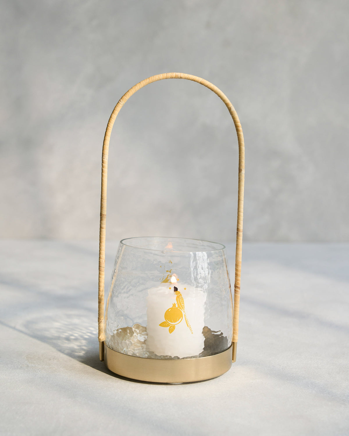 Vesak Lantern with a lit candle inside, showing a gold bird motif.