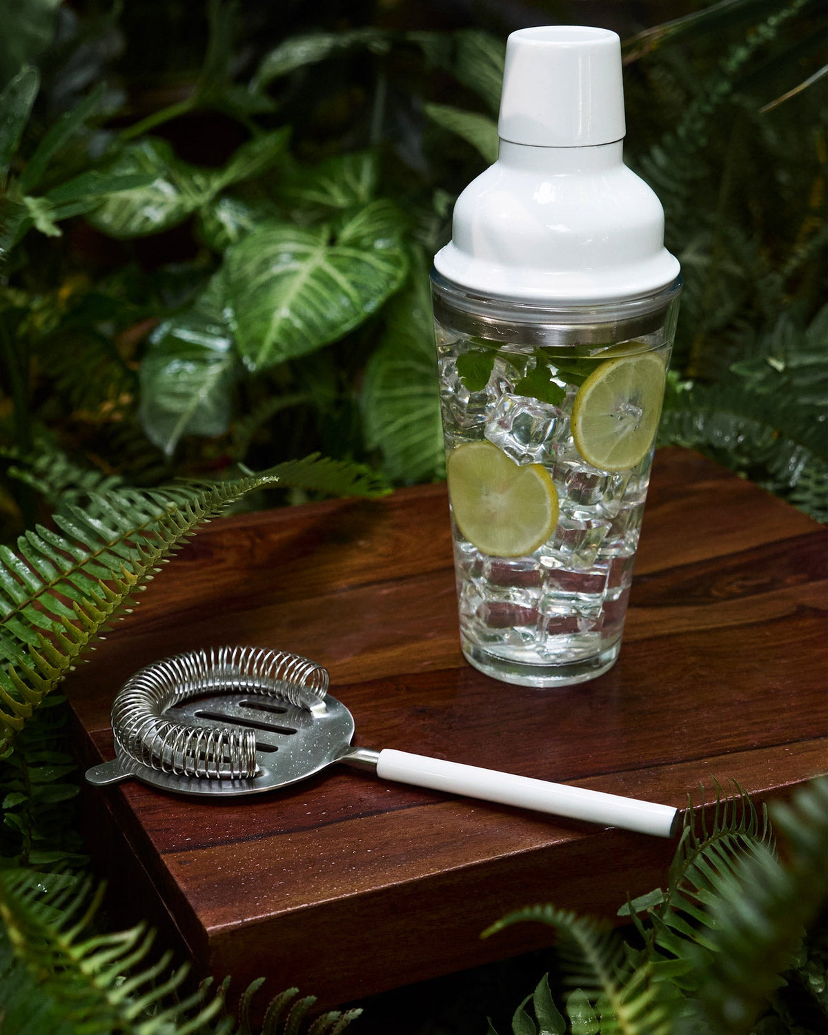 Riverside Cocktail Strainer -White laid alongside a white cocktail shaker.