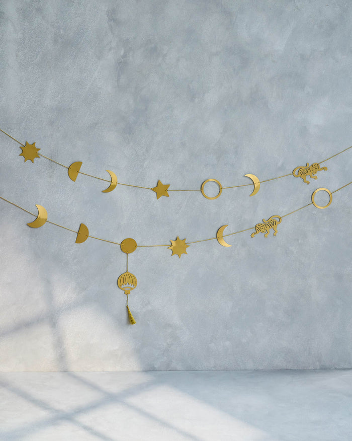 Gold Sumatran Tiger Toran hung on a wall, with moons, stars and a tiger.
