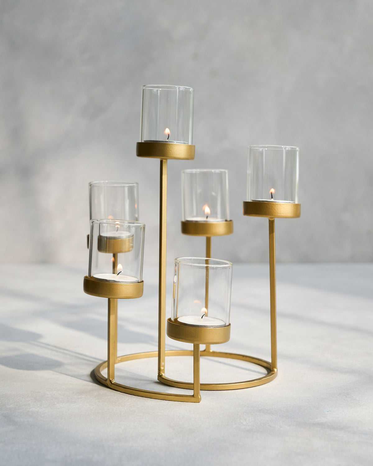 Float Votives gold stand with lit candles inside glass cups.