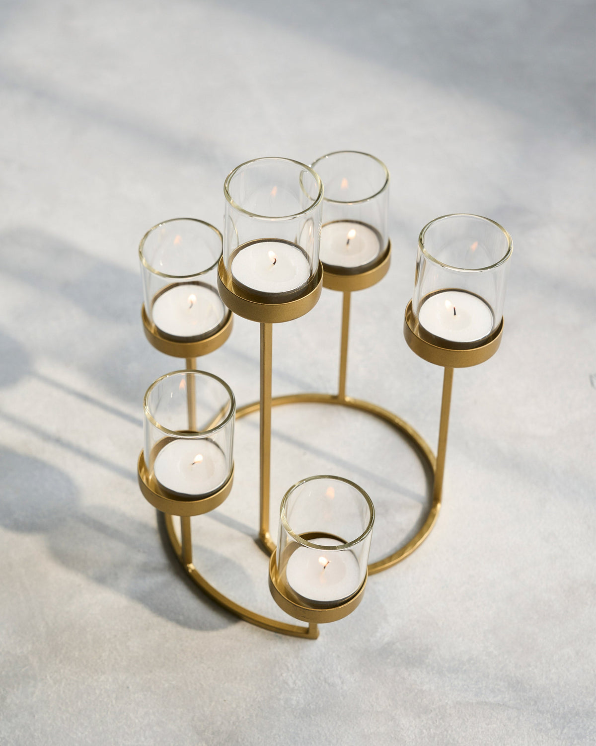 Float Votives gold ring stand with white candles in glass cups.