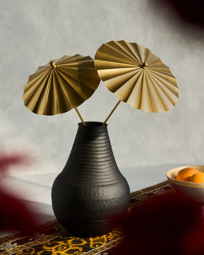 Pair of gold pleated Blossom home accents standing in a black vase.