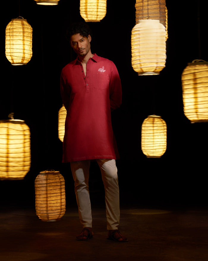Person wearing a red Garnet Kurta with a small white embroidered flower on the pocket.
