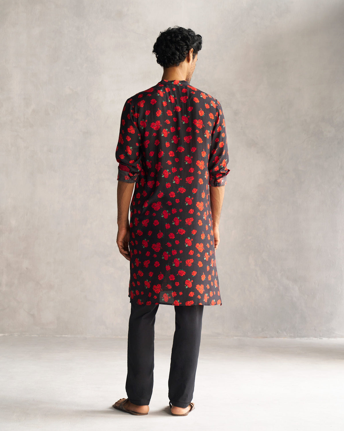 Back of a black Bageecha Kurta with a red rose print, worn by a person.