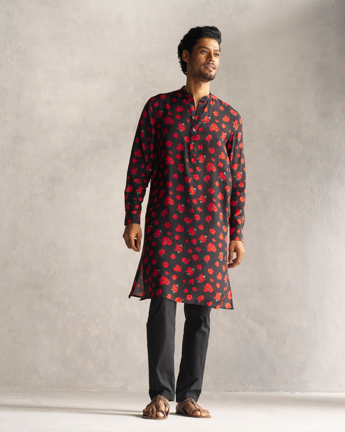 Full-length view of a black Bageecha Kurta with a red rose print worn by a person.
