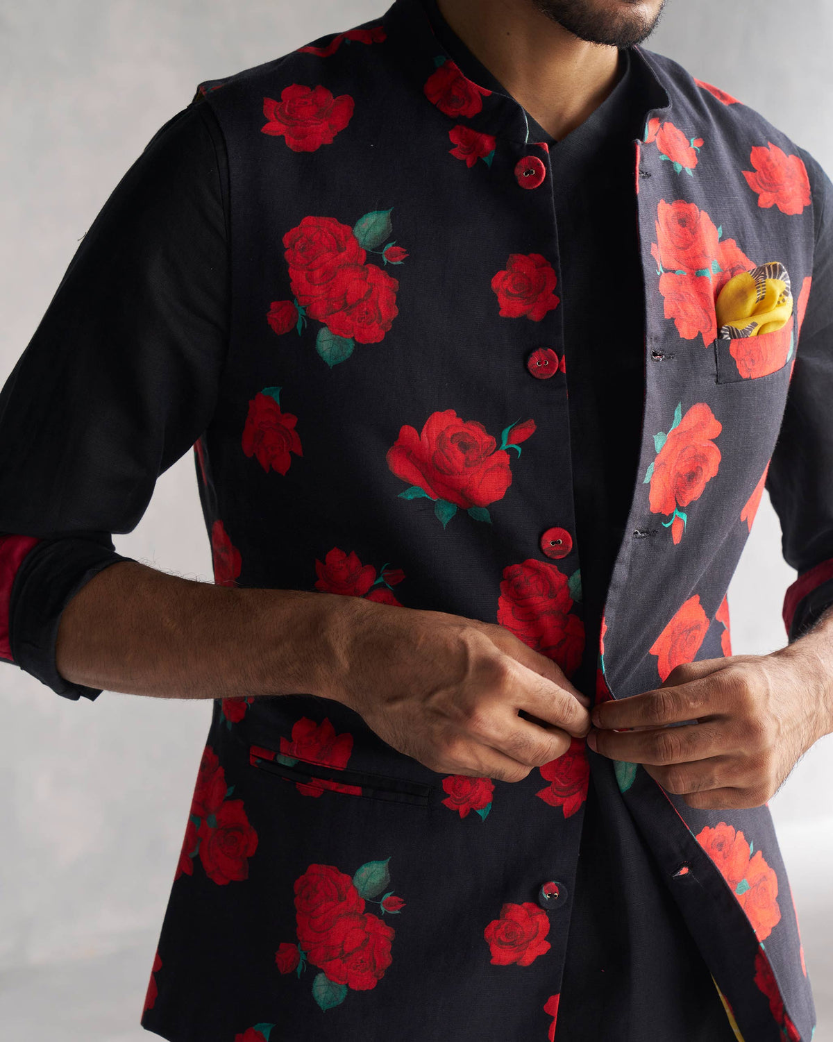 Close-up of a black Nehru Jacket with a red rose print and red buttons.