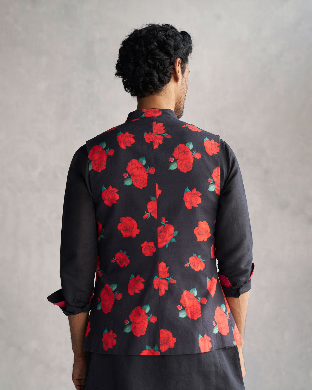 Back of a black Nehru Jacket with a red rose print worn by a person.
