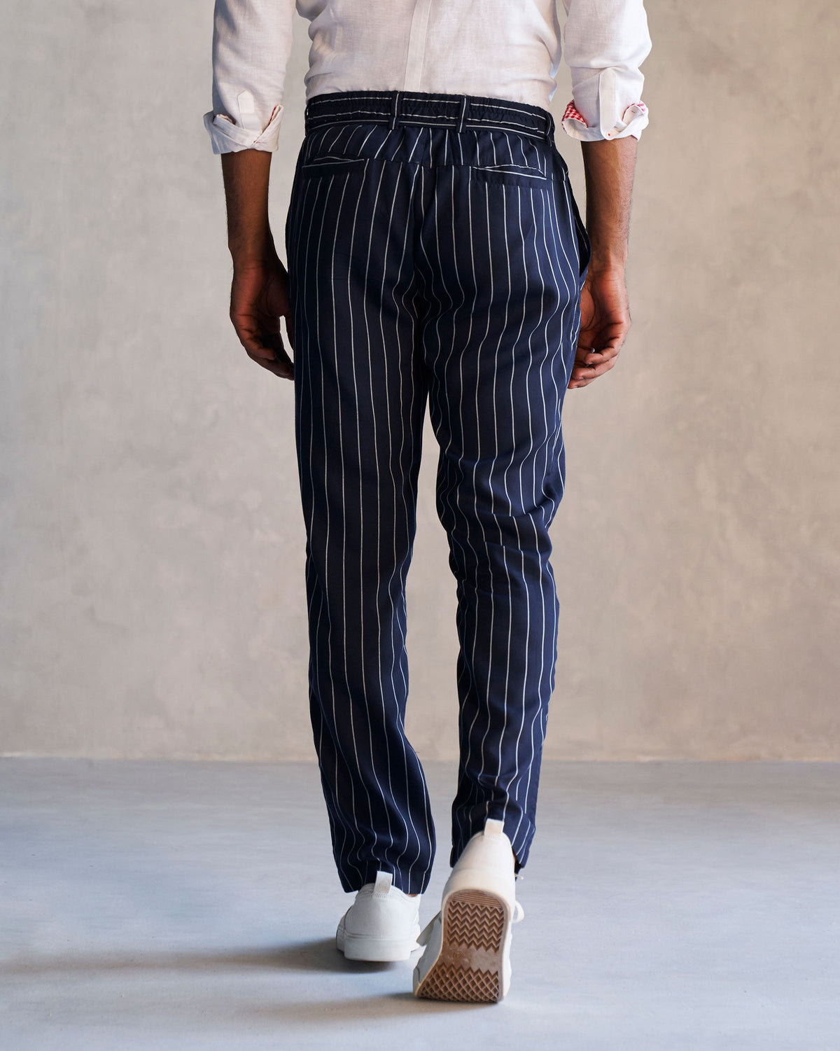 Back of navy Banjara Trousers with white pinstripes worn by a person.