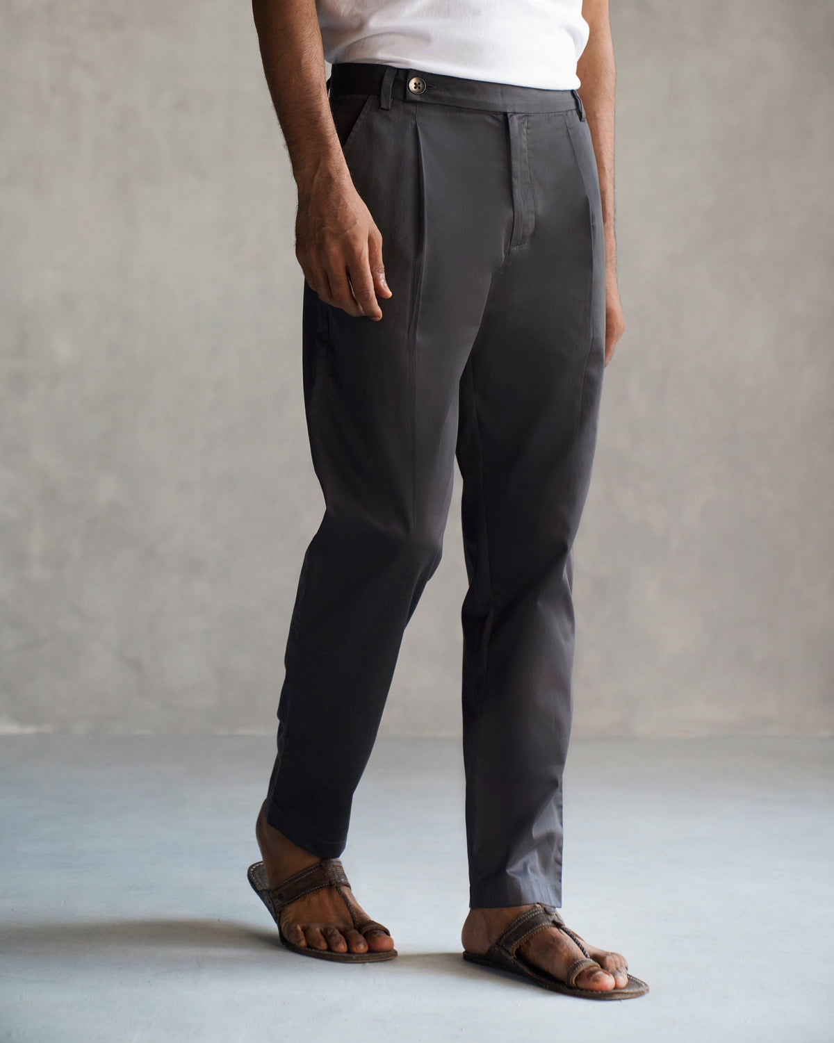 Person wearing dark grey Coast Pants with a button tab at the waist.