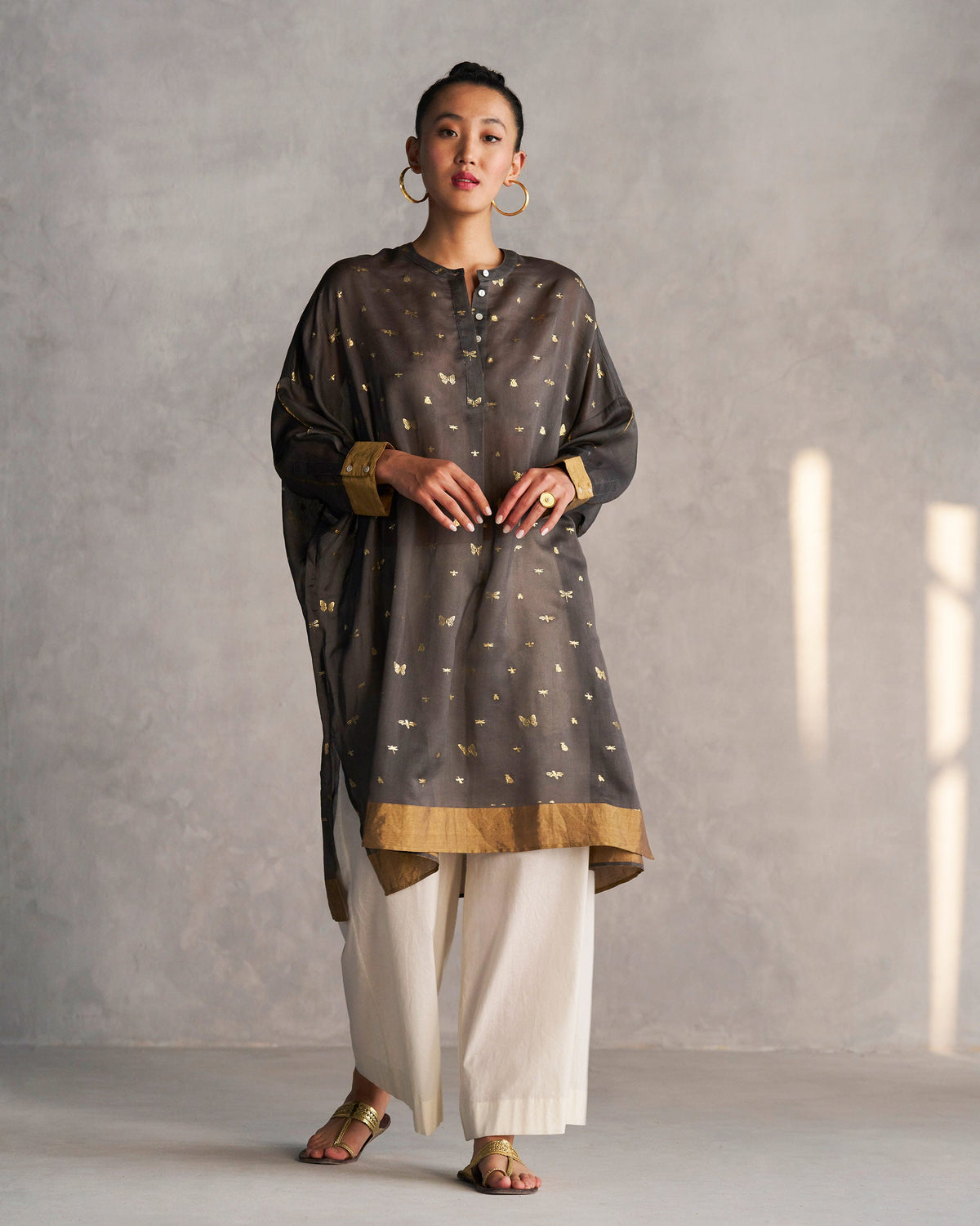 Person standing in a charcoal Lazy Saturday Tunic with a gold hem border.