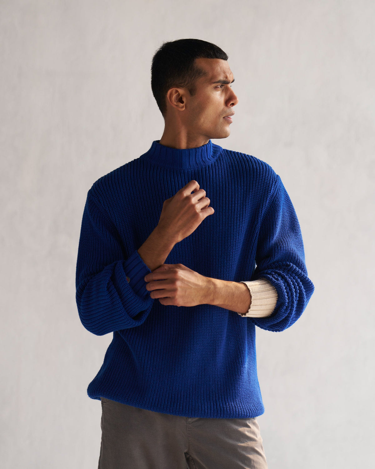 Person wearing a blue Coast sweater with arms folded.
