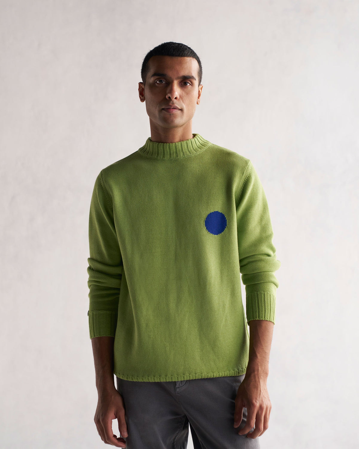 Person wearing green Coast Crew-Neck Sweater with ribbed cuffs and hem.