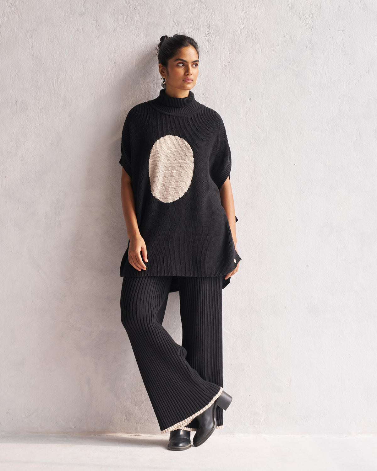 Full-length view of black Ribbed Knit Trousers worn by a person.