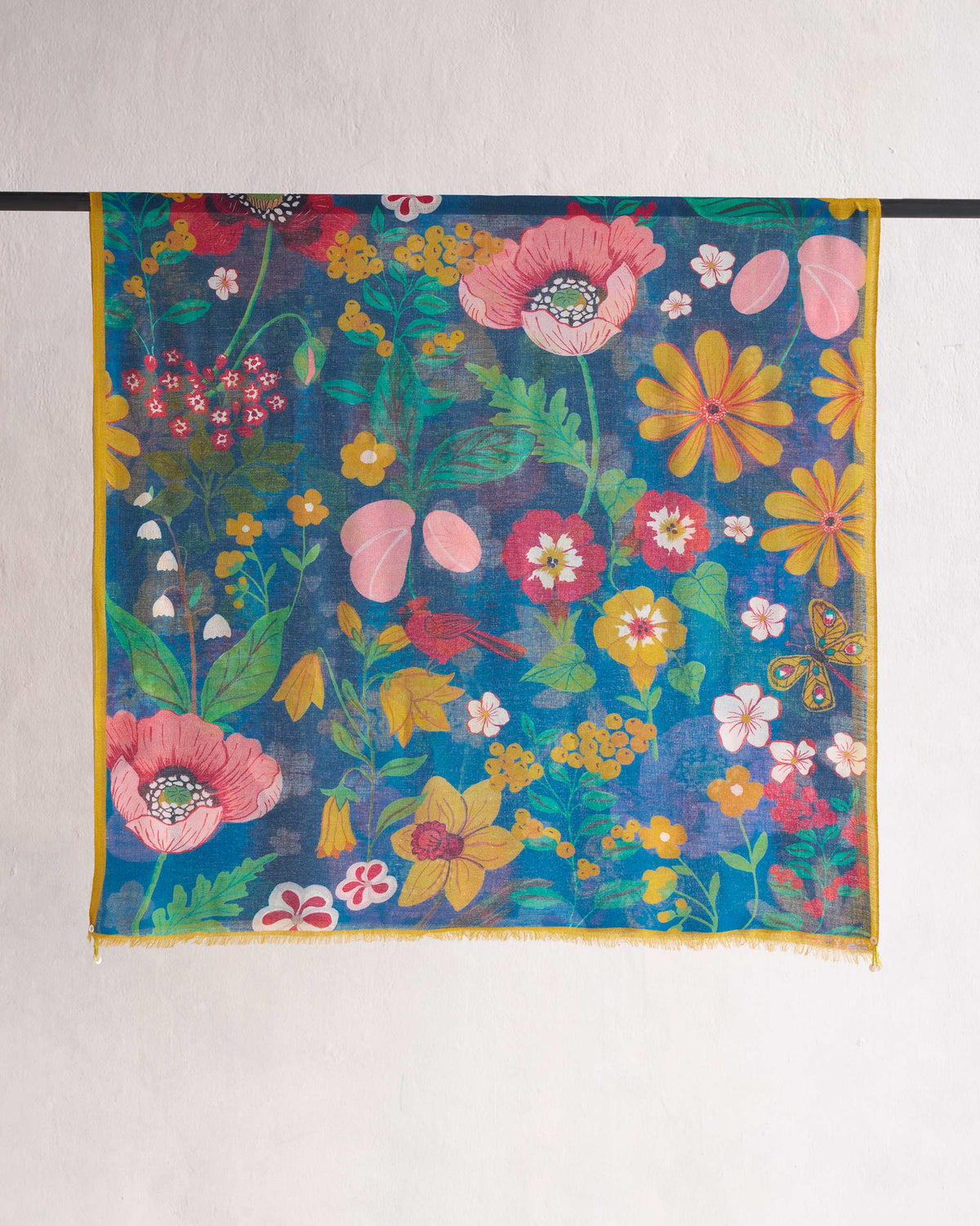 Garden Shawl hung on a rod, teal with pink and yellow flowers and a small bird.