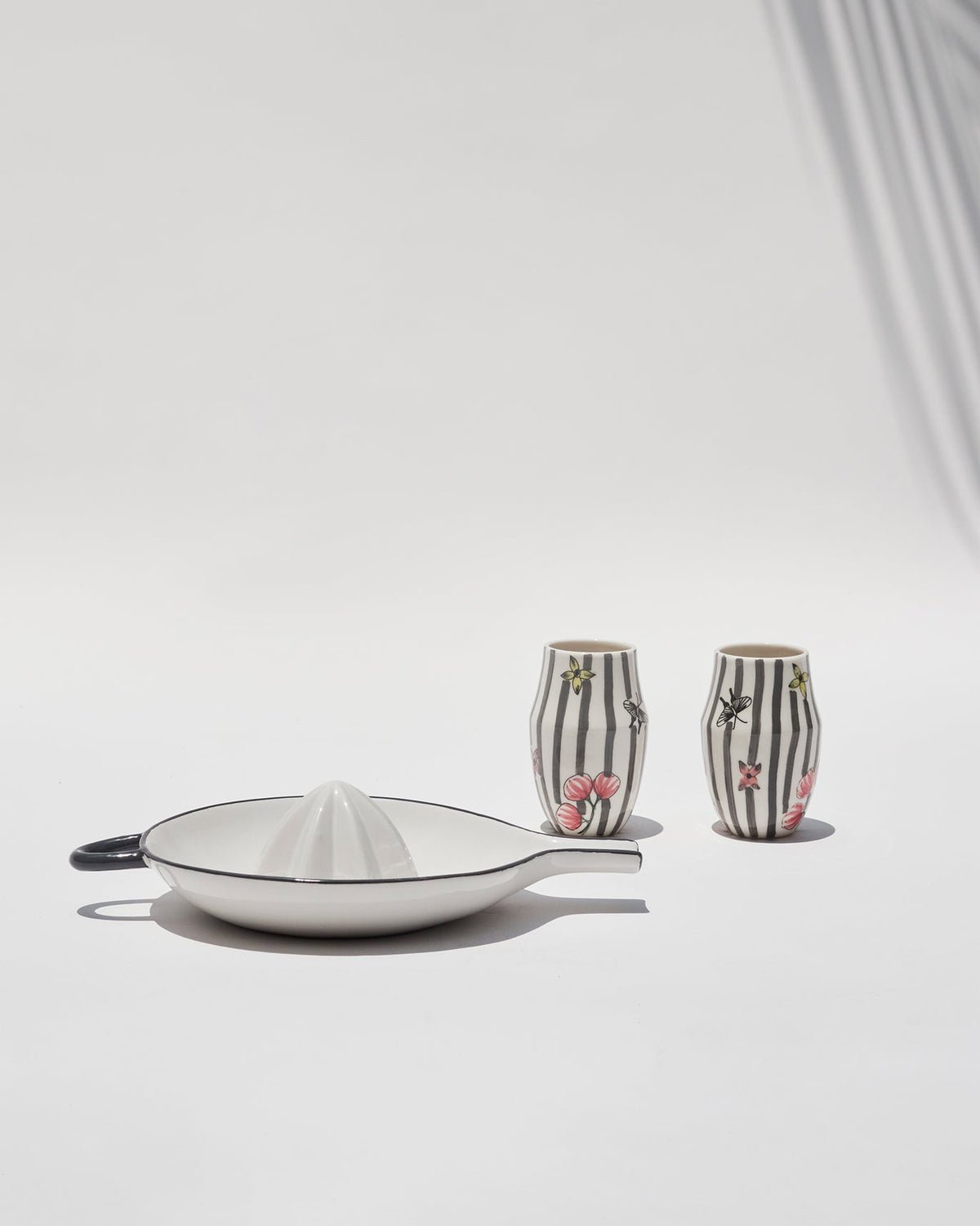 Striped cups standing behind the citrus squeezer in the Just Juice It gift set.