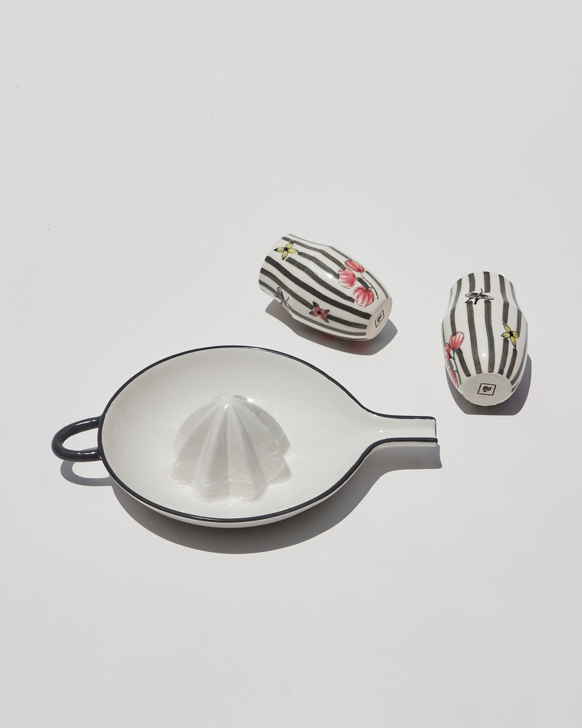 Striped cups from the Just Juice It gift set beside a citrus squeezer.