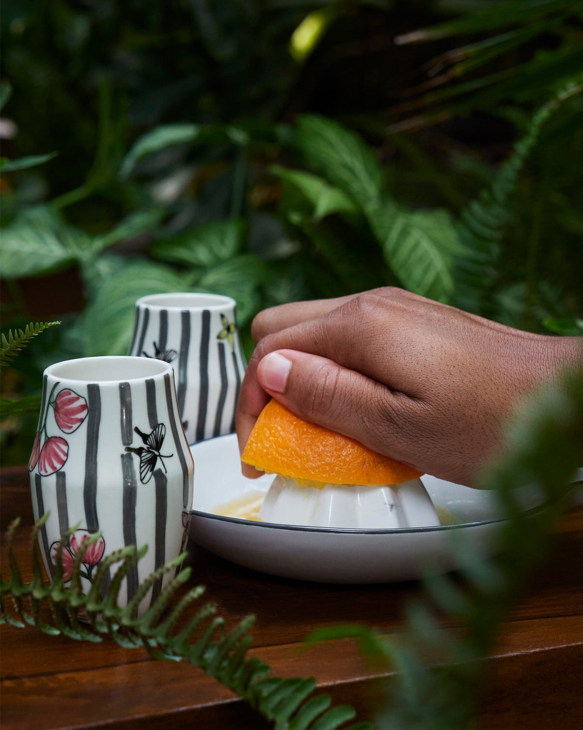 Hand using the citrus squeezer with an orange half in the Just Juice It gift set.