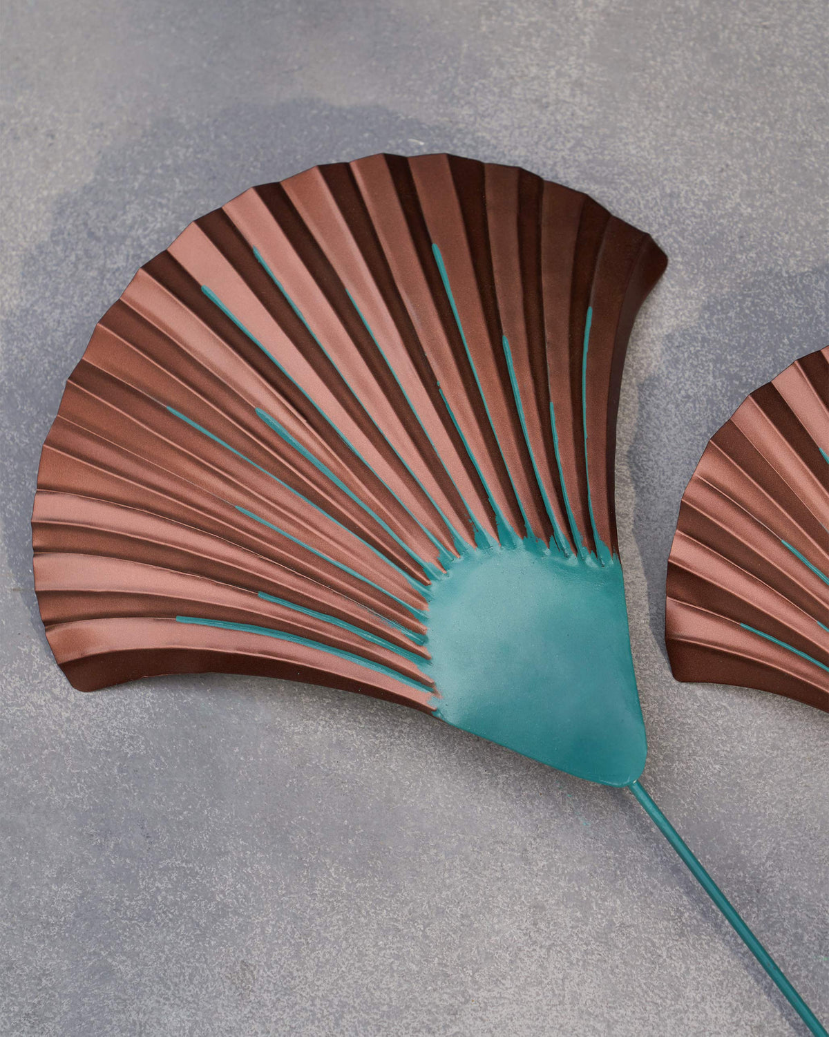 Close-up of a Shell Home Accent showing its ridged copper fan and turquoise base.