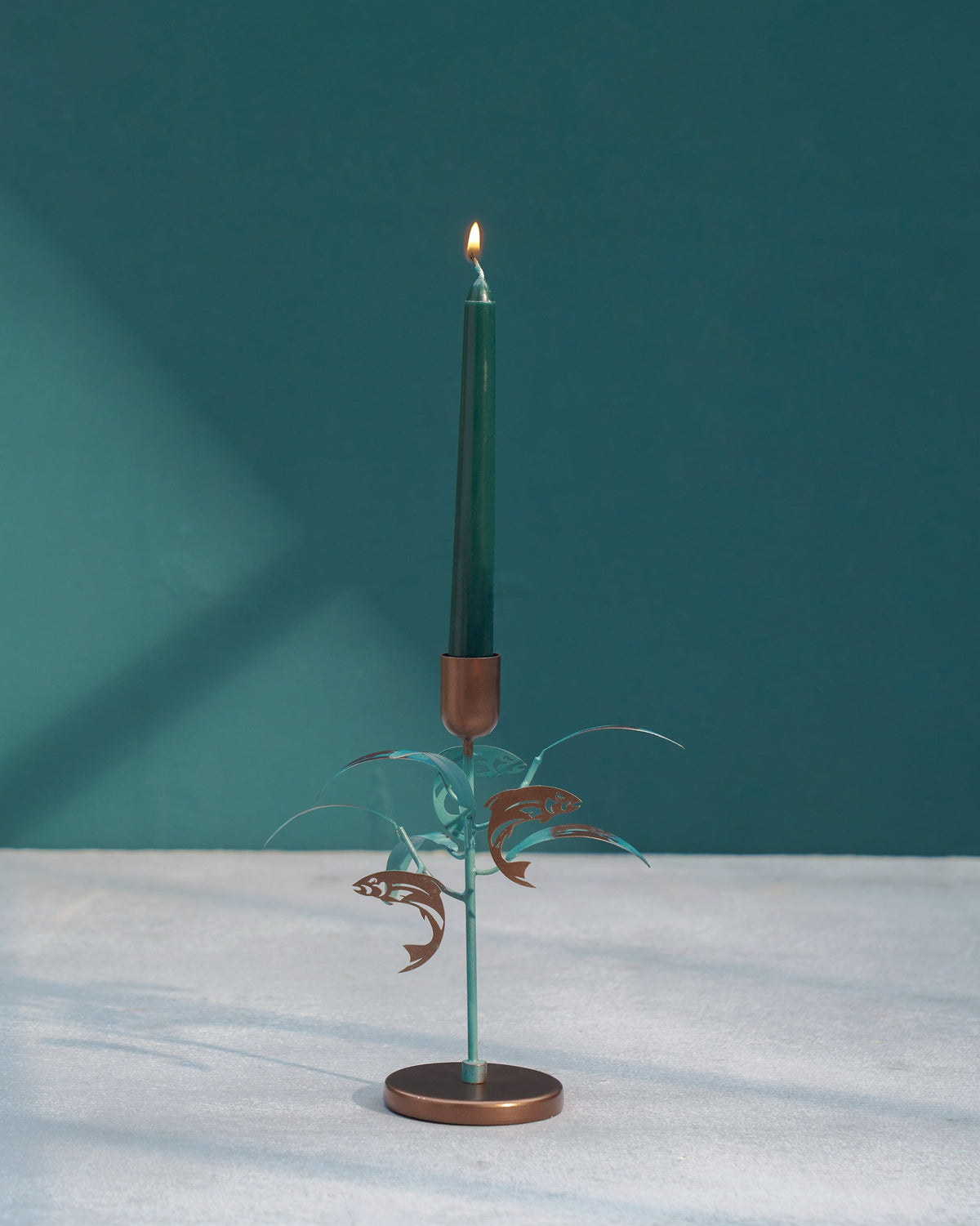 Pacific Candle Stand holding a lit dark green taper.