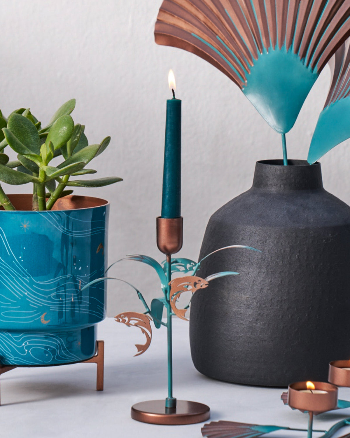 Pacific Candle Stand holding a green taper, placed among decor pieces.