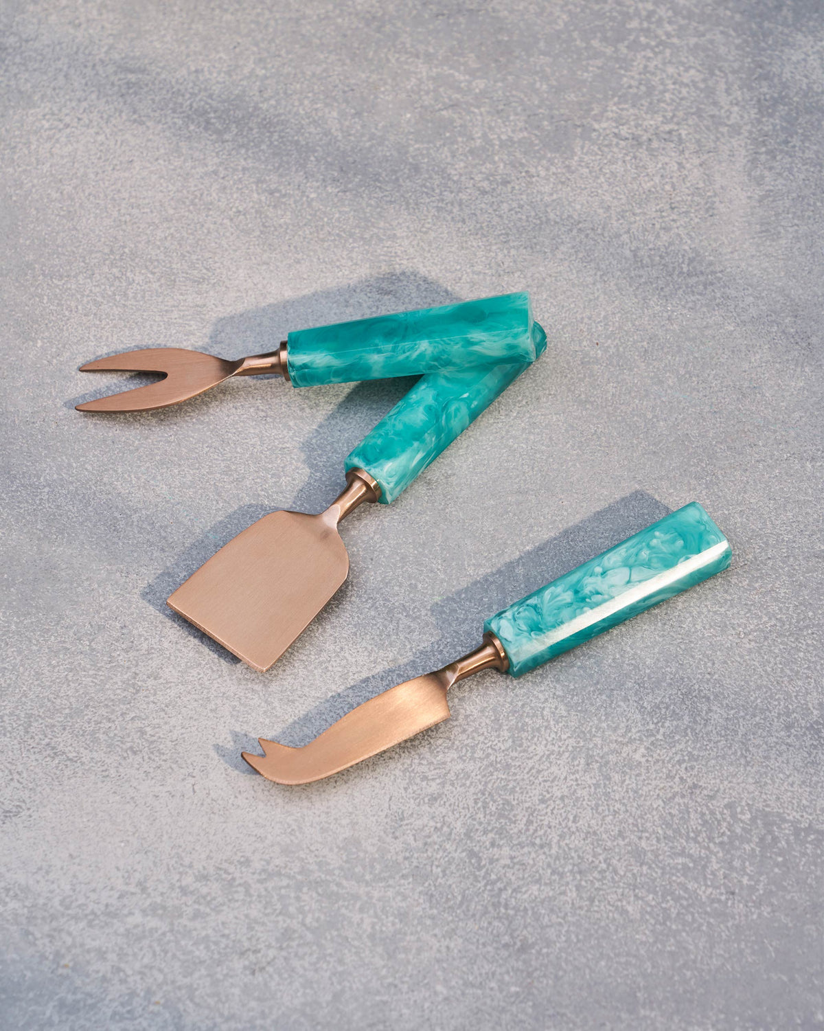 Teal Knife (Set of 3) with a fork and cheese slicer laid out on a grey surface.