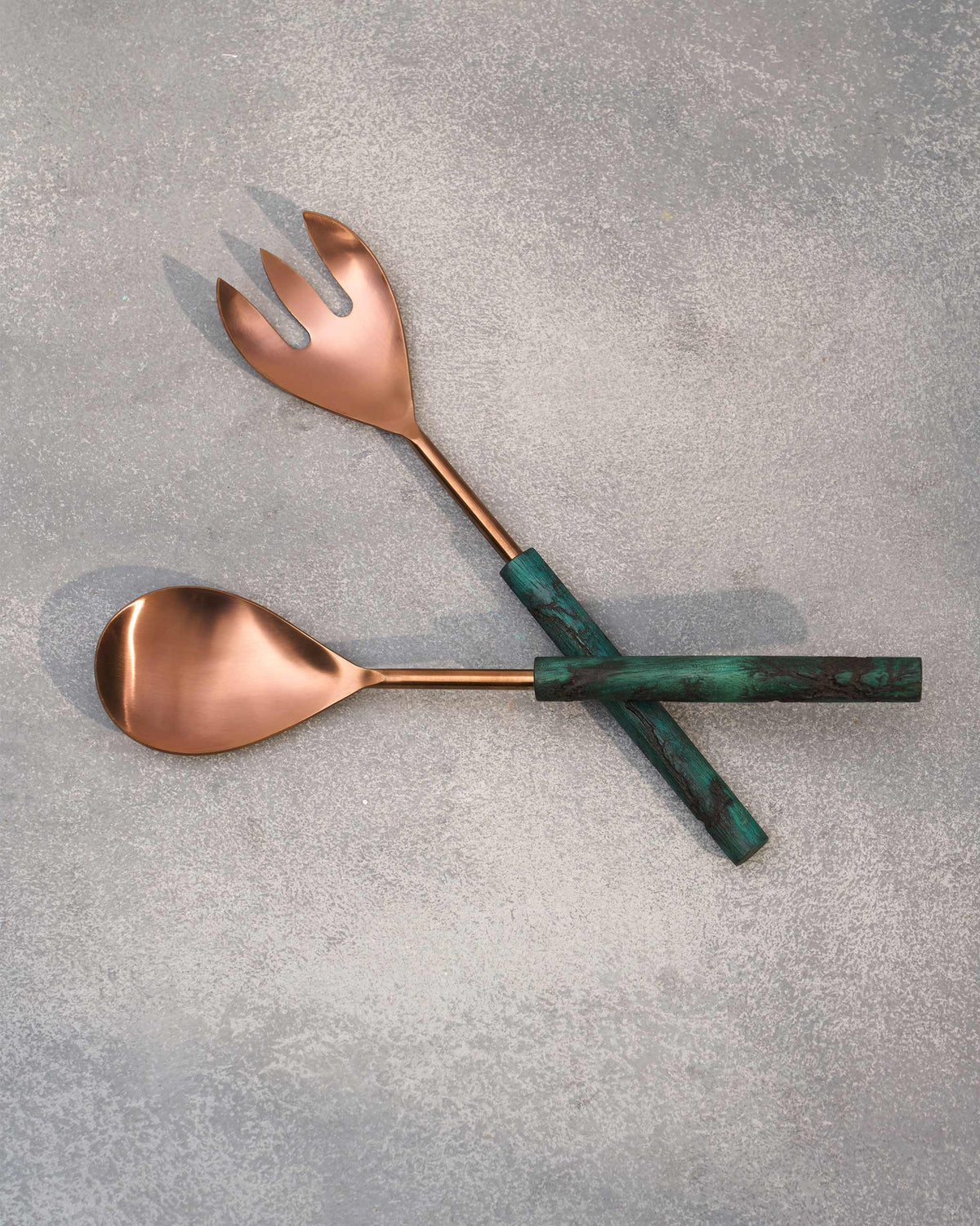 Garden Salad Server spoon and fork crossed on a grey surface.