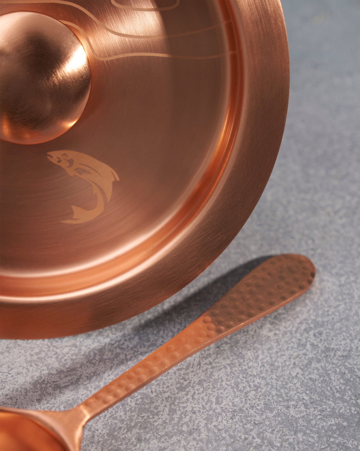 Close-up of the Azure Ice Bucket lid, with a fish engraved on its copper surface.