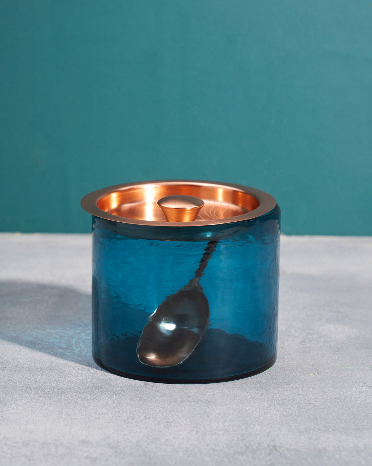 Azure Ice Bucket with its copper lid on and a scoop resting in front.
