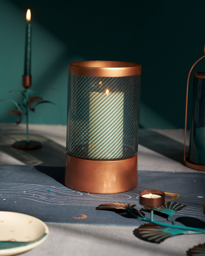 Deco Lantern with a copper rim and base, holding a striped candle.