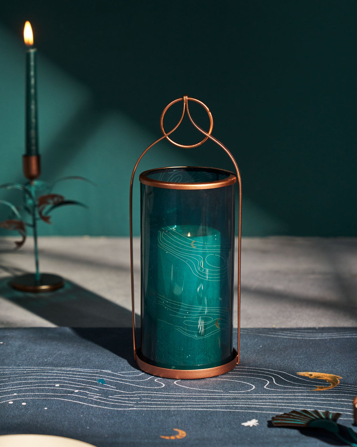 Pacific Lantern with teal glass and a copper frame on a dark table.