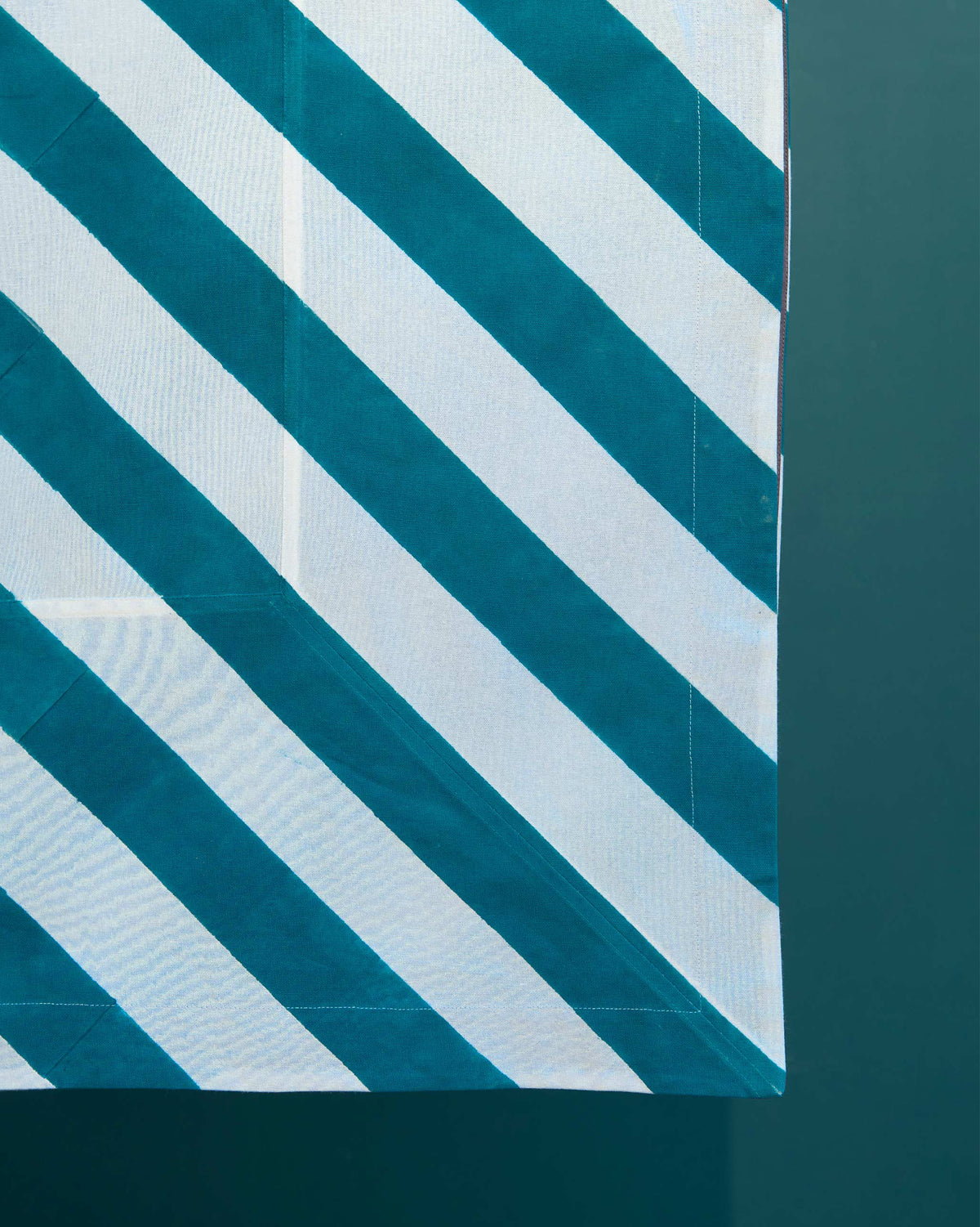 Close-up of the Plush Tablecloth corner in teal and white diagonal stripes.